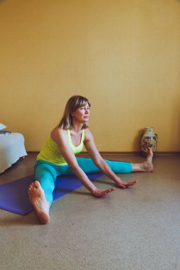 Yetişkin güzel Avrupalı kadın evde yoga yapıyor. Bir dizi yoga pozu. Pashchimottanasana bacakları bükerken sağlıklı yaşam tarzı konsepti, refah kişisel bakım