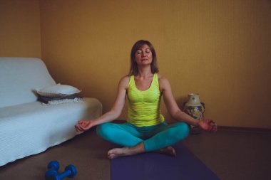 Yetişkin güzel Avrupalı kadın evde yoga yapıyor. Bir dizi yoga pozu. Meditasyon yapıyor Pranayama nefes egzersizi Ardha Padmasana Sağlıklı yaşam tarzı konsepti,