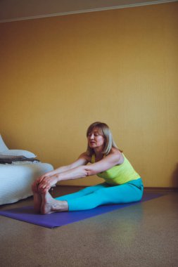 Yetişkin güzel Avrupalı kadın evde yoga yapıyor. Bir dizi yoga pozu. Katla, Pashchimottanasana, sağlıklı yaşam tarzı konsepti, refah kişisel bakım