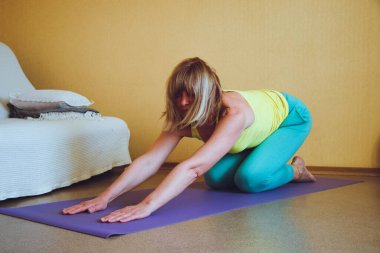 Yetişkin güzel Avrupalı kadın evde yoga yapıyor. Bir dizi yoga pozu. Anand Balasan 'ın çocuğunun pozu. Sağlıklı yaşam tarzı konsepti, refah kişisel bakım