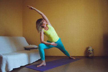 Yetişkin güzel Avrupalı kadın evde yoga yapıyor. Bir dizi yoga pozu. Virabhadrasana savaşçı duruşu. Sağlıklı yaşam tarzı konsepti, refah kişisel bakım