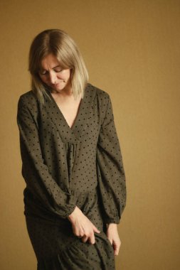 Doğal beyaz saçlı ve minimum makyajlı düşünceli olgun bir kadının sıradan portresi. Kahverengi, gevşek elbiseli.