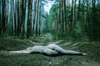 Çevresel kavram, güzel, çıplak, savunmasız genç bir kadın çam ormanında yolda uzanıyor, doğa ve insan arasındaki bağlantı, gezegene saygı..