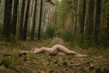 Çevresel kavram, güzel, çıplak, savunmasız genç bir kadın çam ormanında yolda uzanıyor, doğa ve insan arasındaki bağlantı, gezegene saygı..