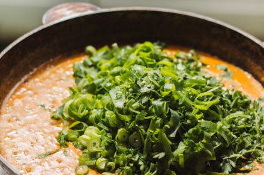 Metal bir tavada Shahi paneer sosu: domates soslu geleneksel bir Hint paneer peyniri tabağı. Ve bir sürü yeşillik. Üst görünüm kapat