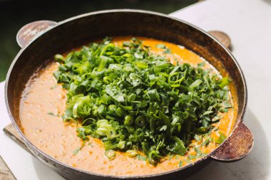 Metal bir tavada Shahi paneer sosu: domates soslu geleneksel bir Hint paneer peyniri tabağı. Ve bir sürü yeşillik. Üst görünüm kapat