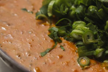 Metal bir tavada Shahi paneer sosu: domates soslu geleneksel bir Hint paneer peyniri tabağı. Ve bir sürü yeşillik. Üst görünüm kapat