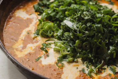 Metal bir tavada Shahi paneer sosu: domates soslu geleneksel bir Hint paneer peyniri tabağı. Ve bir sürü yeşillik. Üst görünüm kapat