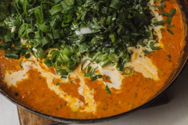 Metal bir tavada Shahi paneer sosu: domates soslu geleneksel bir Hint paneer peyniri tabağı. Ve bir sürü yeşillik. Üst görünüm kapat