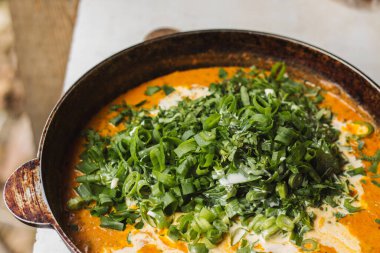 Metal bir tavada Shahi paneer sosu: domates soslu geleneksel bir Hint paneer peyniri tabağı. Ve bir sürü yeşillik. Üst görünüm kapat