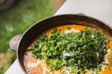 Metal bir tavada Shahi paneer sosu: domates soslu geleneksel bir Hint paneer peyniri tabağı. Ve bir sürü yeşillik. Üst görünüm kapat