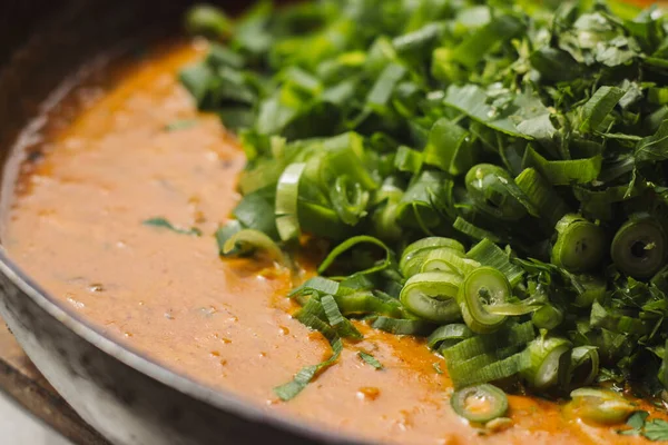 Metal bir tavada Shahi paneer sosu: domates soslu geleneksel bir Hint paneer peyniri tabağı. Ve bir sürü yeşillik. Üst görünüm kapat