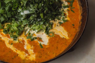 Metal bir tavada Shahi paneer sosu: domates soslu geleneksel bir Hint paneer peyniri tabağı. Ve bir sürü yeşillik. Üst görünüm kapat