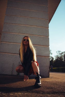 Kırmızı elbiseli ve siyah deri ceketli güzel bir kadının sokak portresi. Eski mavi duvarın yanında