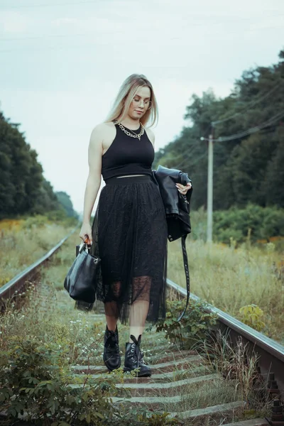 黒い服の若い美しい少女は 鉄道線路の上 良い気分で美しいブロンド 美しい自然の柔らかい夜の光 — ストック写真