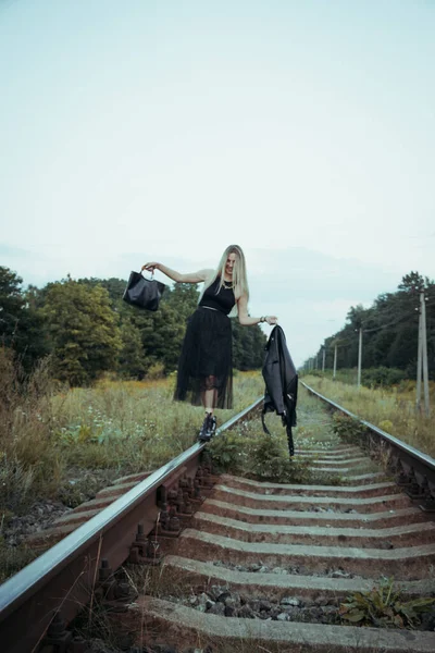 黒い服の若い美しい少女は 鉄道線路の上 良い気分で美しいブロンド 美しい自然の柔らかい夜の光 — ストック写真