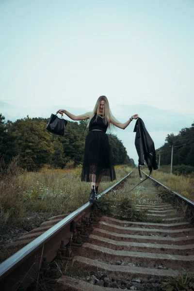 黒い服の若い美しい少女は 鉄道線路の上 良い気分で美しいブロンド 美しい自然の柔らかい夜の光 — ストック写真