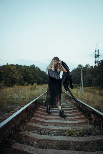 黒い服の若い美しい少女は 鉄道線路の上 良い気分で美しいブロンド 美しい自然の柔らかい夜の光 — ストック写真