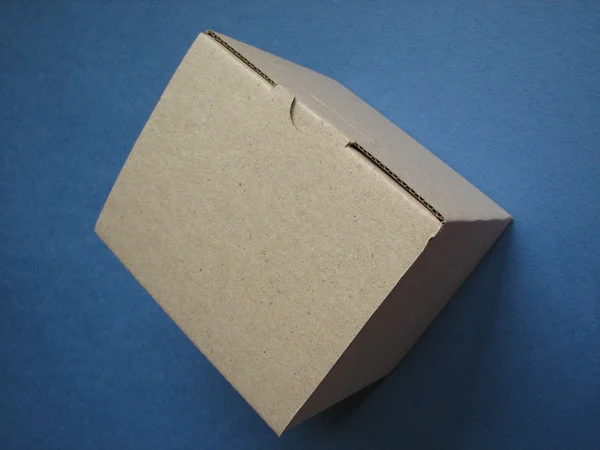 Caixa de papelão em um fundo azul escuro — Fotografia de Stock