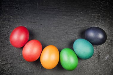 Renkli paskalya yumurtaları - üst görünüm, siyah arka plan üzerinde gülümseme şeklinde düz yatar