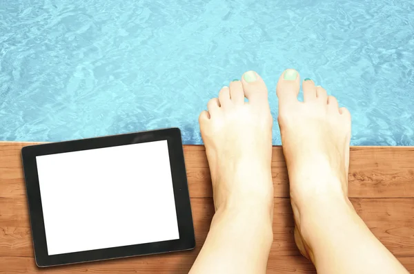 Piernas de mujer con tableta de pantalla en blanco en la piscina — Foto de Stock