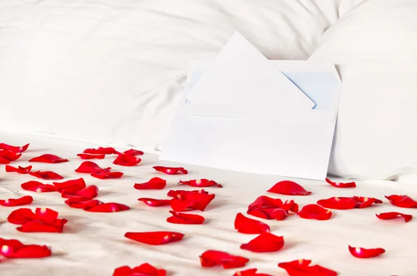 장미 꽃잎 가운데 침대에 봉투 — 스톡 사진