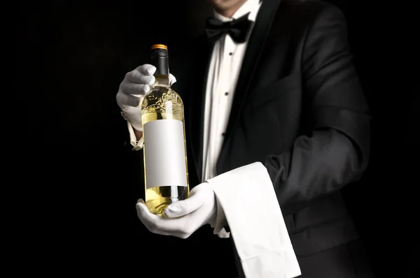 Camarero con esmoquin sosteniendo una botella de vino blanco — Foto de Stock