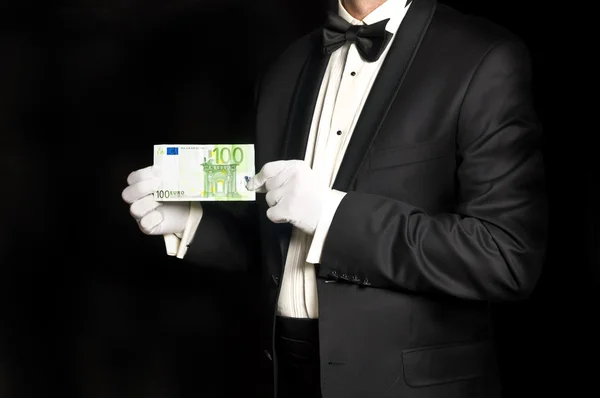 Eleganta mannen i smoking håller 100-eurosedeln Stockbild