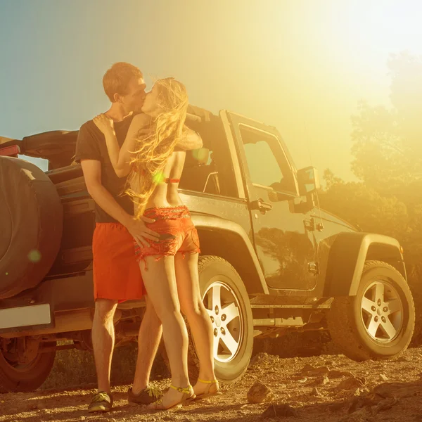 คู่รักจูบกันข้างๆ ขับรถ 4 ทิศทางตอนพระอาทิตย์ตก — ภาพถ่ายสต็อก