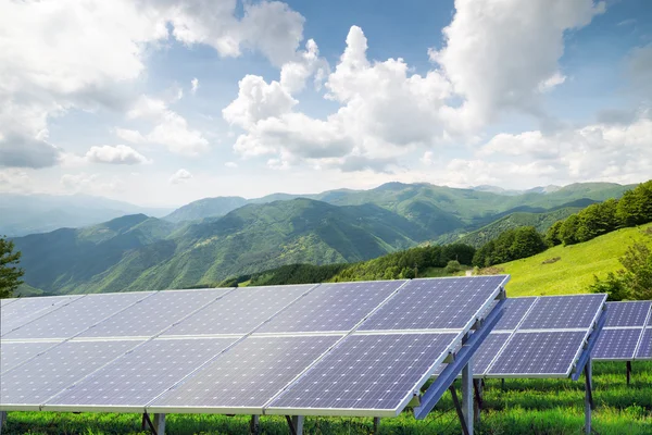 Painéis solares contra a paisagem montanhosa contra o céu azul com c — Fotografia de Stock