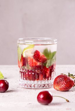 Yazın çilekli tatlı vişneli kokteyl. Gri arka planda buzlu içecek. Boşluğu kopyala