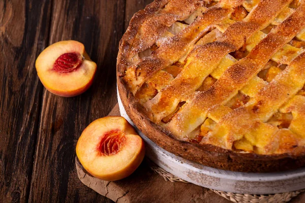 Homemade sweet pie cake with peach on white board on wooden rustic background.