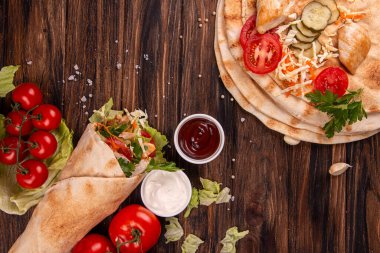 Popüler Arap Türklerinin fast food bağışçısı shawarma dürümü. Eti, sebzesi ve ahşap arka planda malzemeleri var. Üst Manzara. Boşluğu kopyala