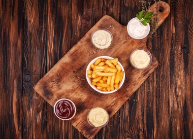 Patates kızartması, patates kızartması ve ahşap arka planda soslar. en üstteki görünüm