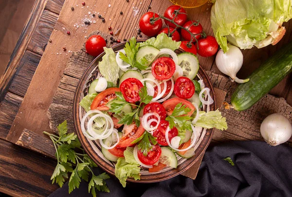 Vegetable salad of white onion, cucumber, tomatoes, lettuce, parsley on rustic background. Low carb dietary food. Top view