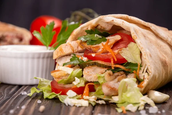 Popüler Arap Türklerinin fast food bağışçısı shawarma dürümü. Eti, sebzesi ve ahşap arka planda malzemeleri var. en üstteki görünüm