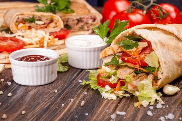 Popüler Arap Türklerinin fast food bağışçısı shawarma dürümü. Eti, sebzesi ve ahşap arka planda malzemeleri var. en üstteki görünüm
