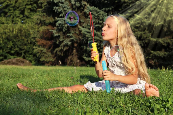 Menina no parque soprando bolhas — Fotografia de Stock