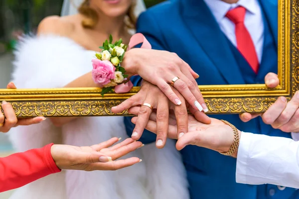 Noivo e noiva mostrar seus anéis através da moldura — Fotografia de Stock