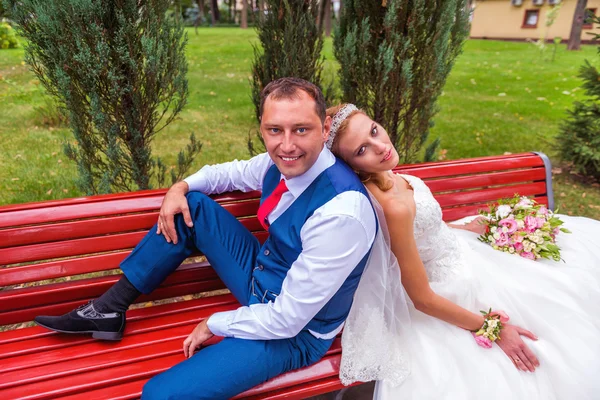 Noiva e noivo casamento sentado no banco no parque — Fotografia de Stock