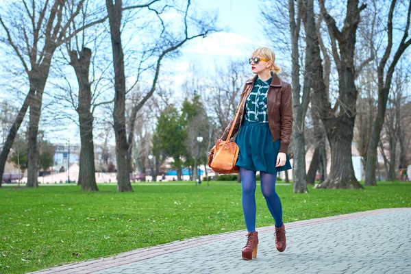 Молода жінка з сумкою, що йде в парку — стокове фото