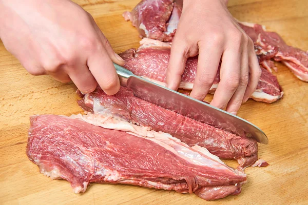 Fette di carne cruda tagliate con coltello su tavola di legno — Foto Stock