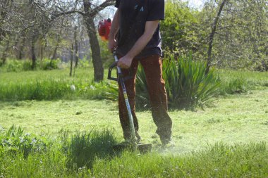 Gaz keskisi olan bir adam çimleri biçiyor. 