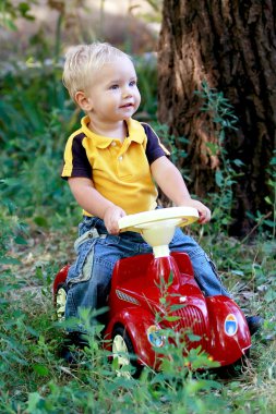 Yeni kırmızı araba üzerinde küçük bir çocuk oturur