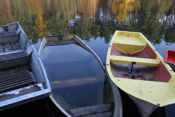 Three boats on the dock, reflected in the blue water green trees — Stock Photo, Image