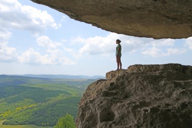 Bir kız grotto yüksek bir dağın üzerinde duruyor.