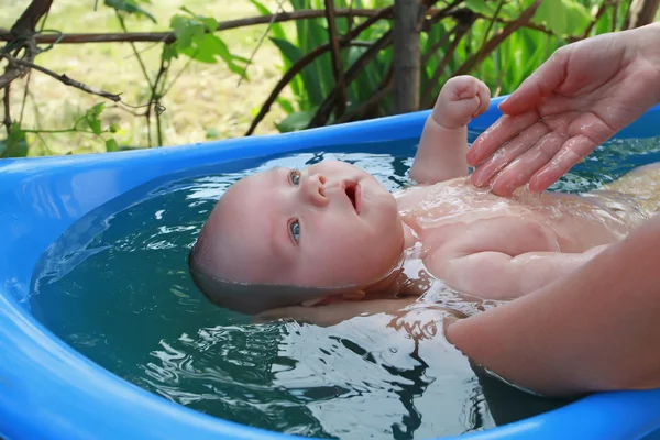 Vader rolt jonge zoon in een kruiwagen met tuingereedschap in de achtertuin van zijn huis. Een man met een baard-boer zet de baby in een kruiwagen met tools. Little Helper op de boerderij met een bebaarde vader — Stockfoto