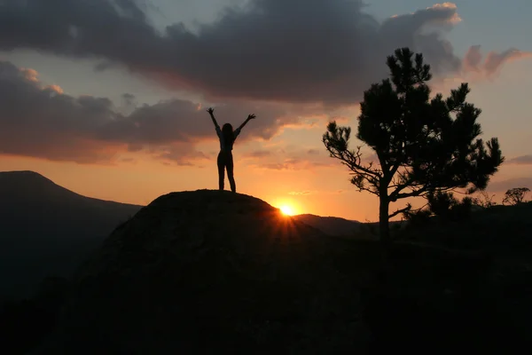 一个女孩站在一座山上，与他举起手来 ag 的剪影 — 图库照片