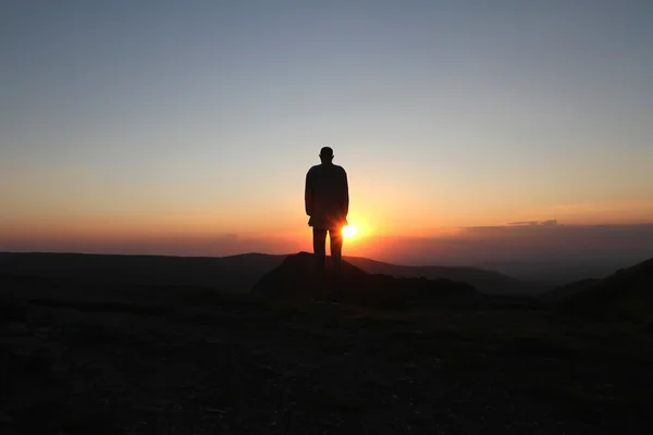 Um homem está na montanha e cumprimenta o sol nascente — Fotografia de Stock