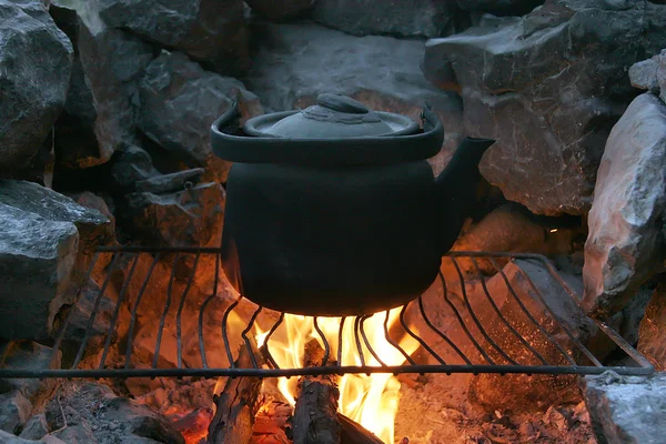 Ferva a chaleira no fogo em condições de campo. Cozinhar café da manhã em um campo de refugiados . — Fotografia de Stock